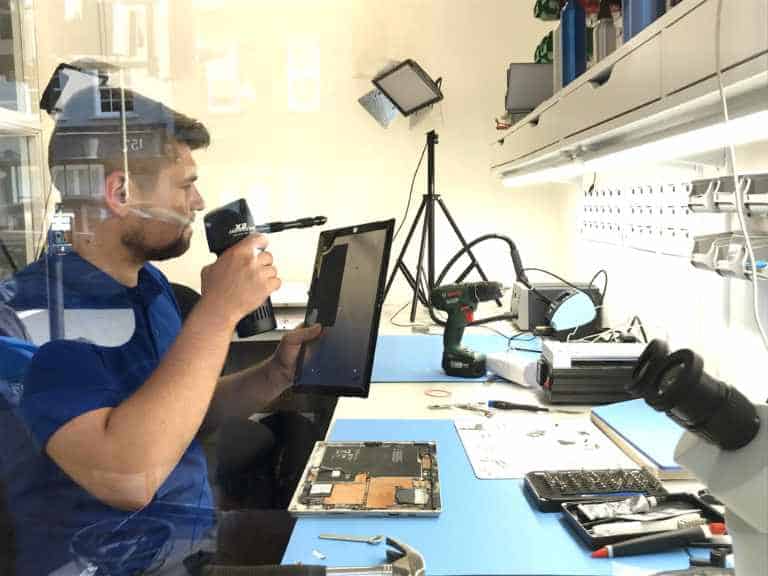 A technician checking the camera lens on a replacement Surface screen before fitting it
