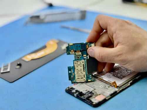 Fixfactor Phone Motherboard On The Blue Matt Standing With Hand