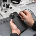 Technician inspecting an iPhone rear camera module during diagnosis