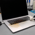 Technician unplugging a MacBook after a coffee spill