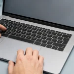 Technician testing the built-in keyboard and trackpad on a MacBook-style laptop