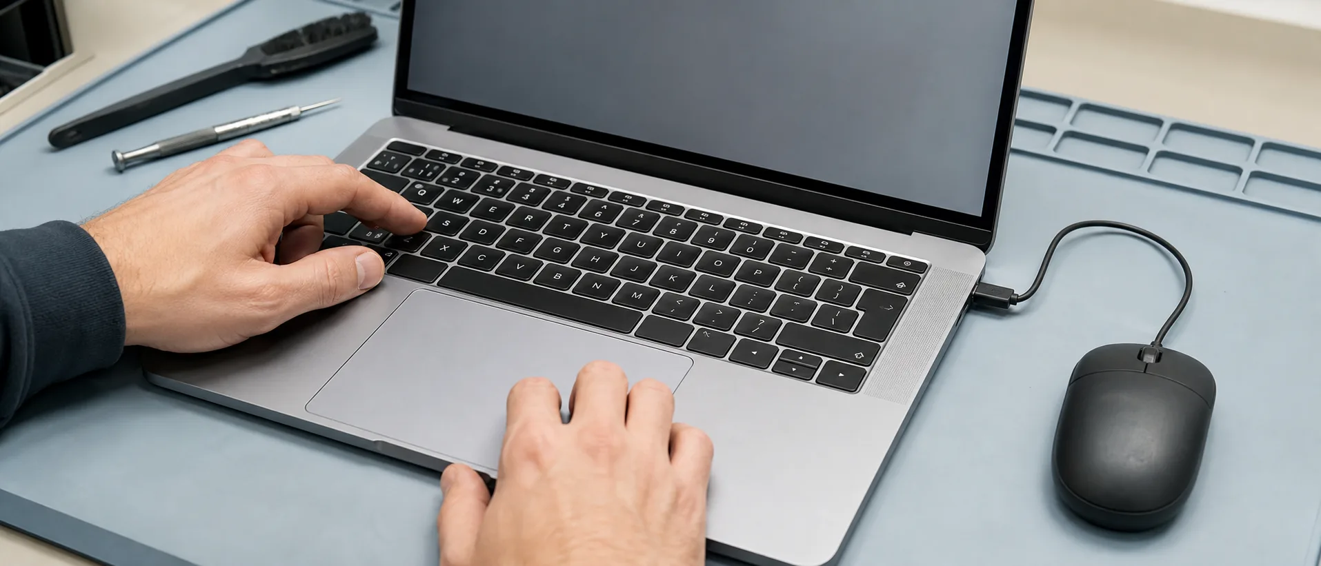 Technician testing the built-in keyboard and trackpad on a MacBook-style laptop