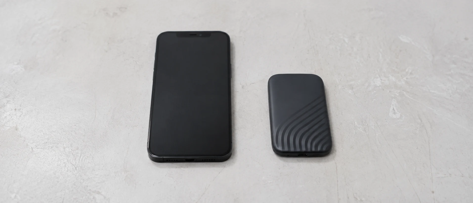 Illustration of a phone with its screen off beside a portable backup drive